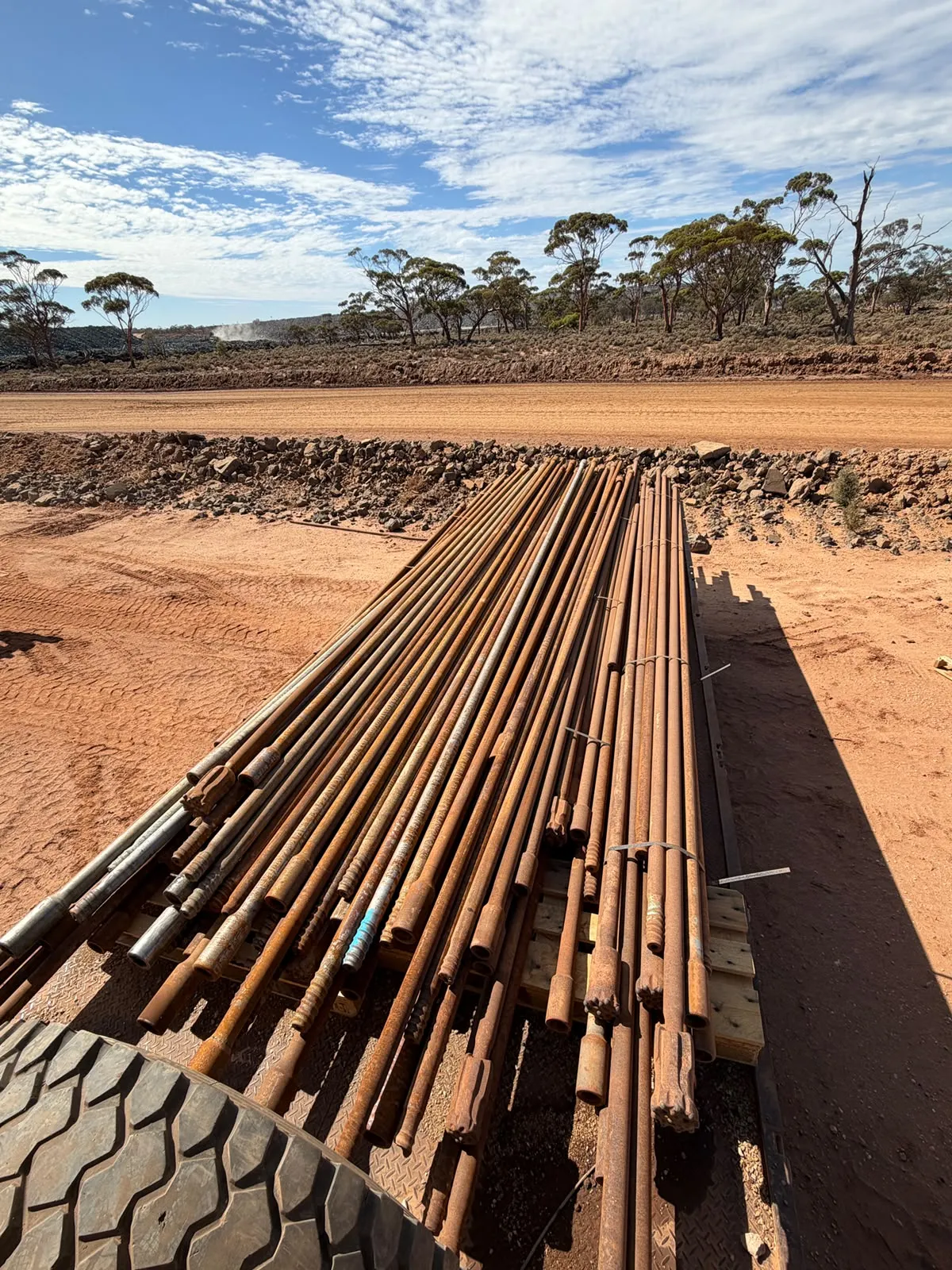 Pallet of used drill rods beside a red dirt road in regional WA