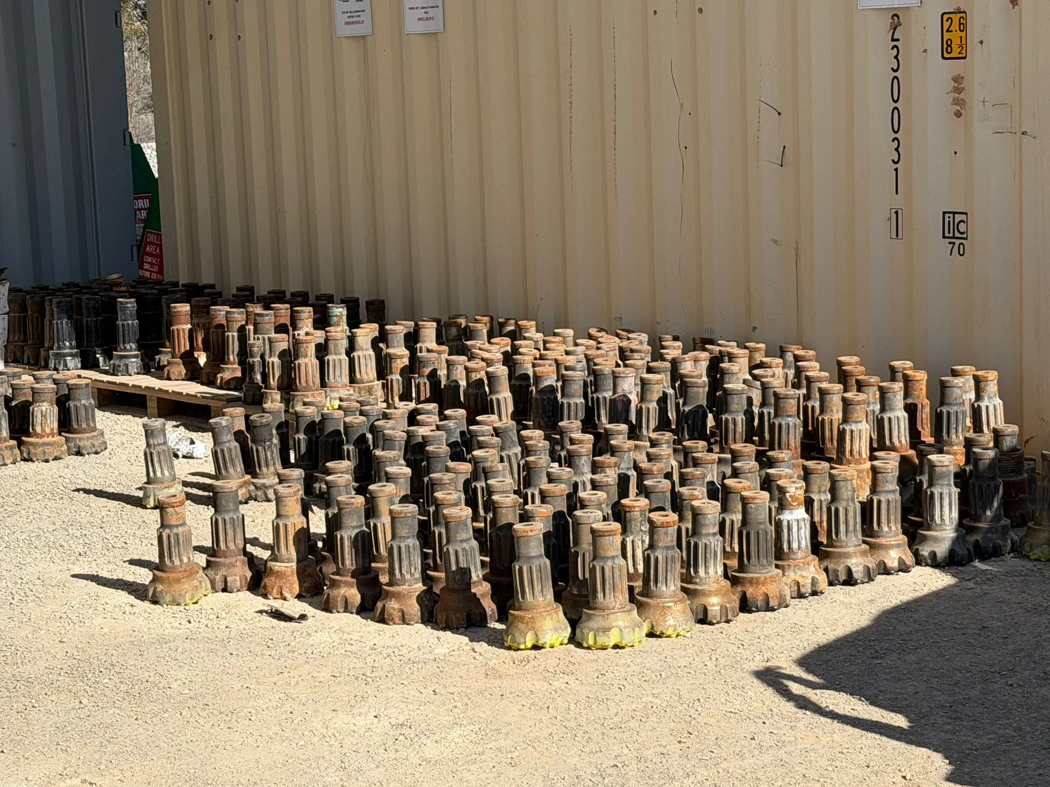 Rows of worn DTH hammer bits laid out for inspection in the yard